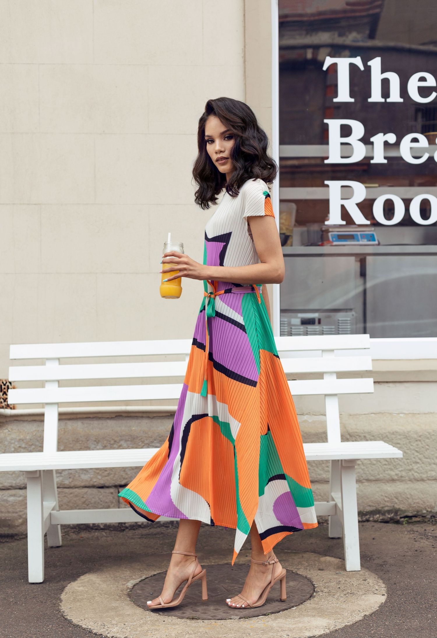 Woman in colorful geometric print midi dress holding drink outside The Break Room.