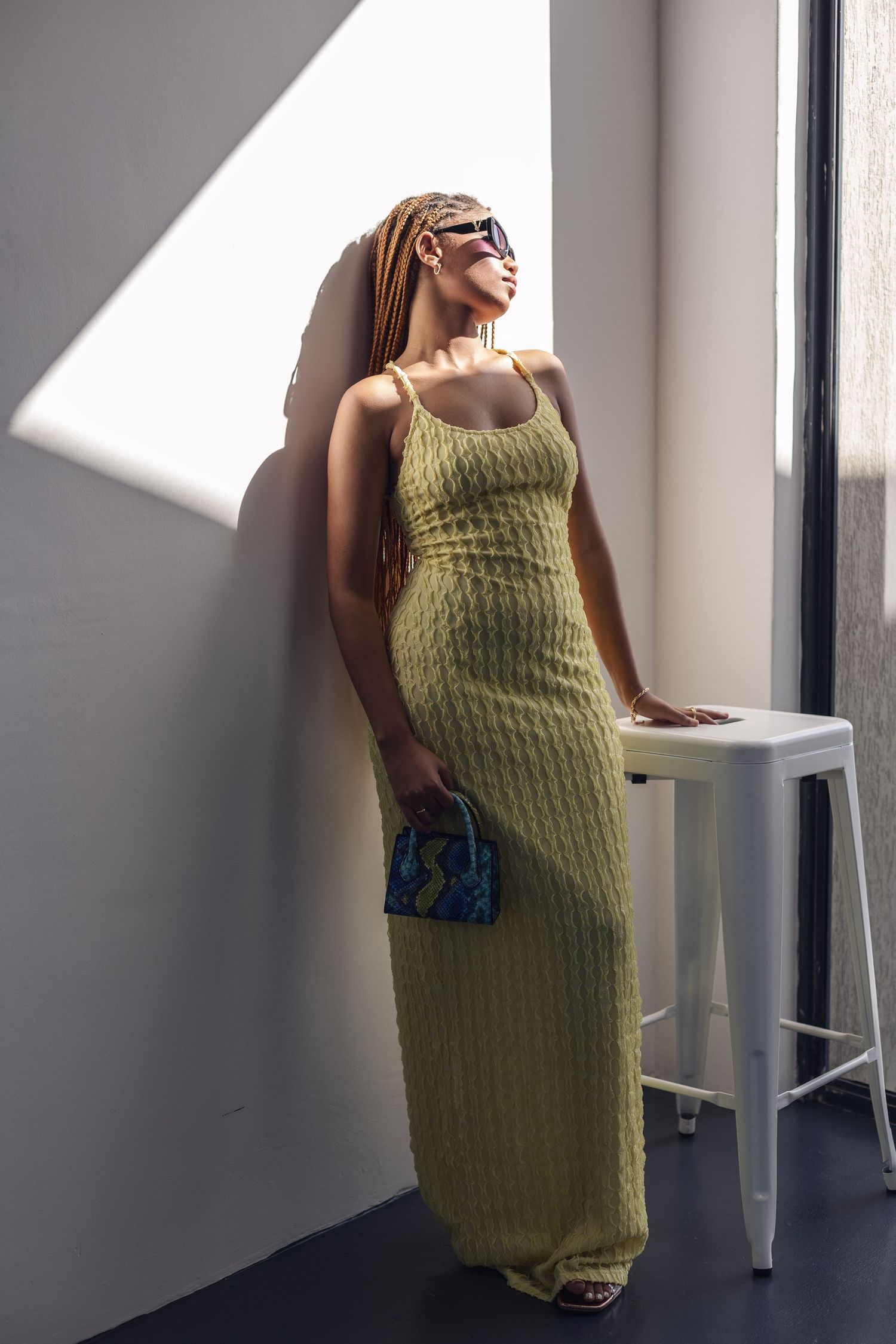 Fashion photography of model in yellow knit dress posing by window.