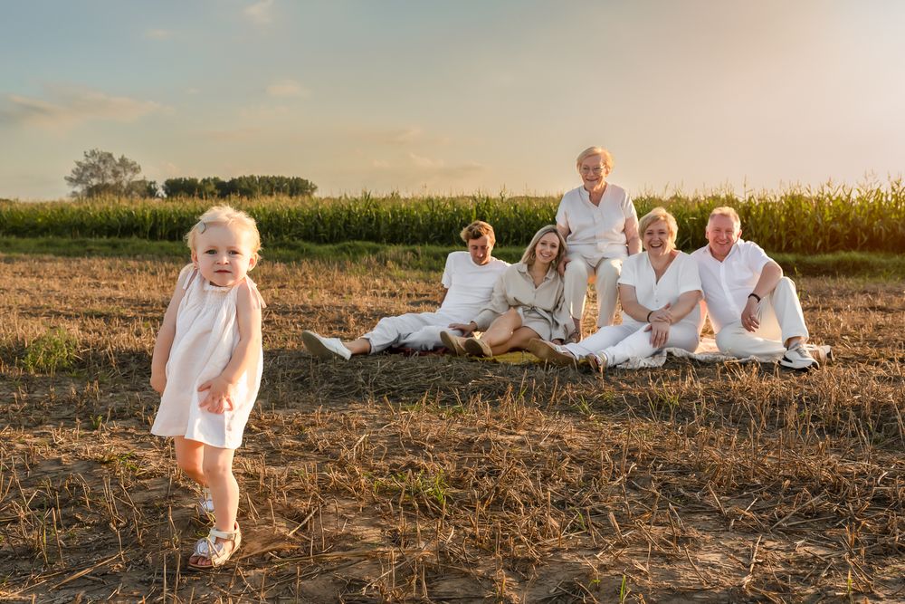 A playful scene unfolds during a family photoshoot at sunset in a rural field.