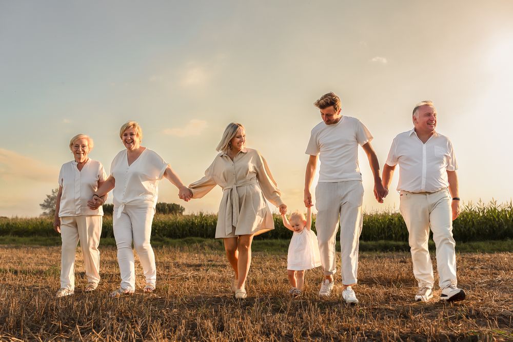 A group walks together hand-in-hand through a sun-drenched field at golden hour.