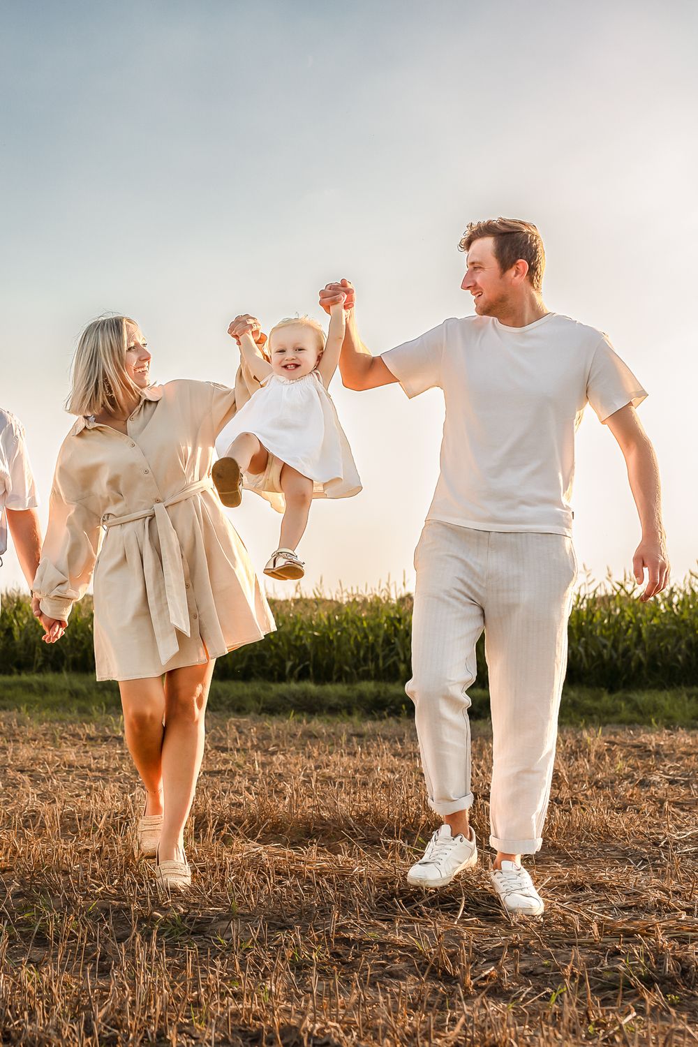 A joyful moment shared between people in white outfits during sunset in a rural field.
