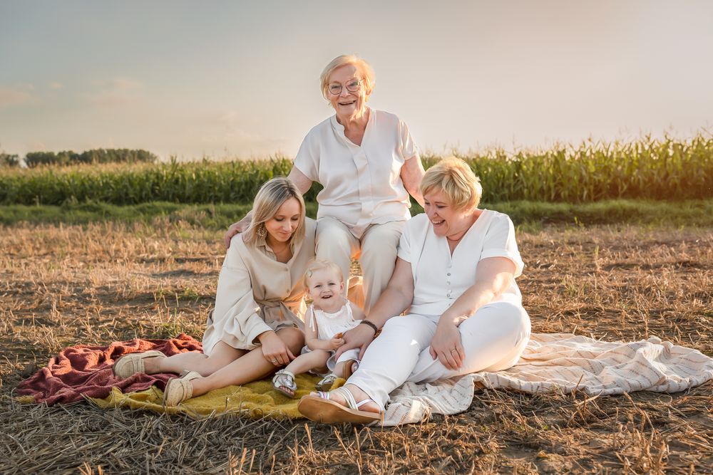 A cheerful gathering picnics together at golden hour in a rural field wearing matching white clothing.