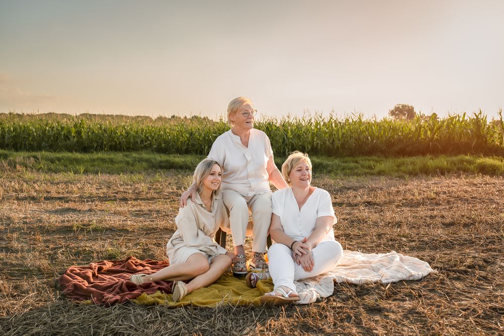 Family group sitting on blankets for outdoor portrait during golden hour.