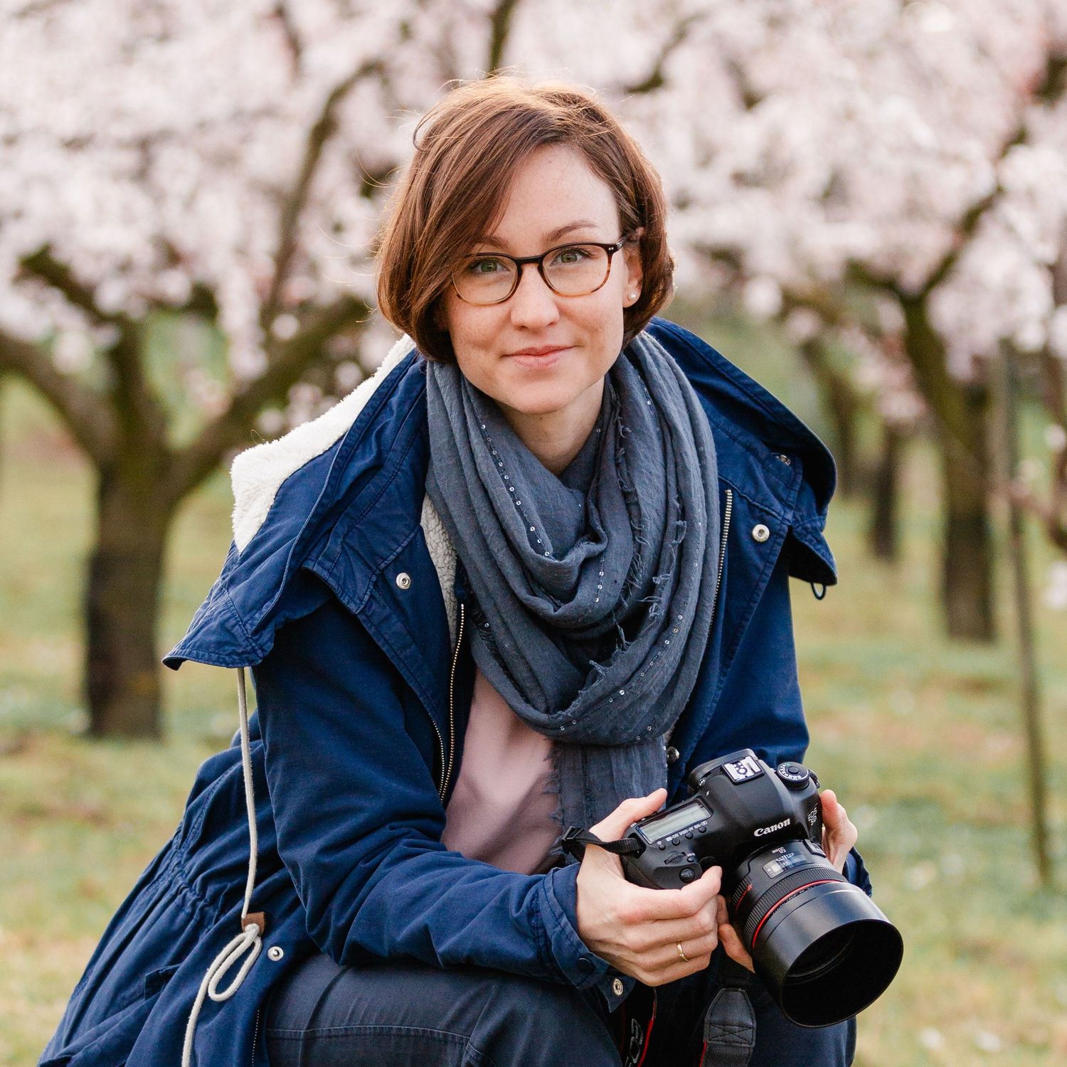 Porträt der Fotografin Margarethe mit ihrer Kamera in der Hand im blühenden Marillengarten