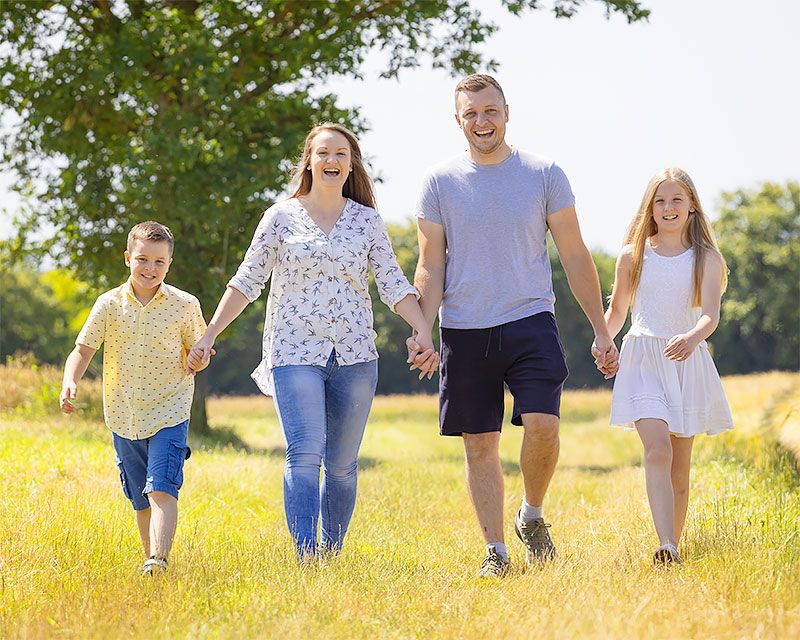 A family walking together hand in hand through a sunny summer meadow.