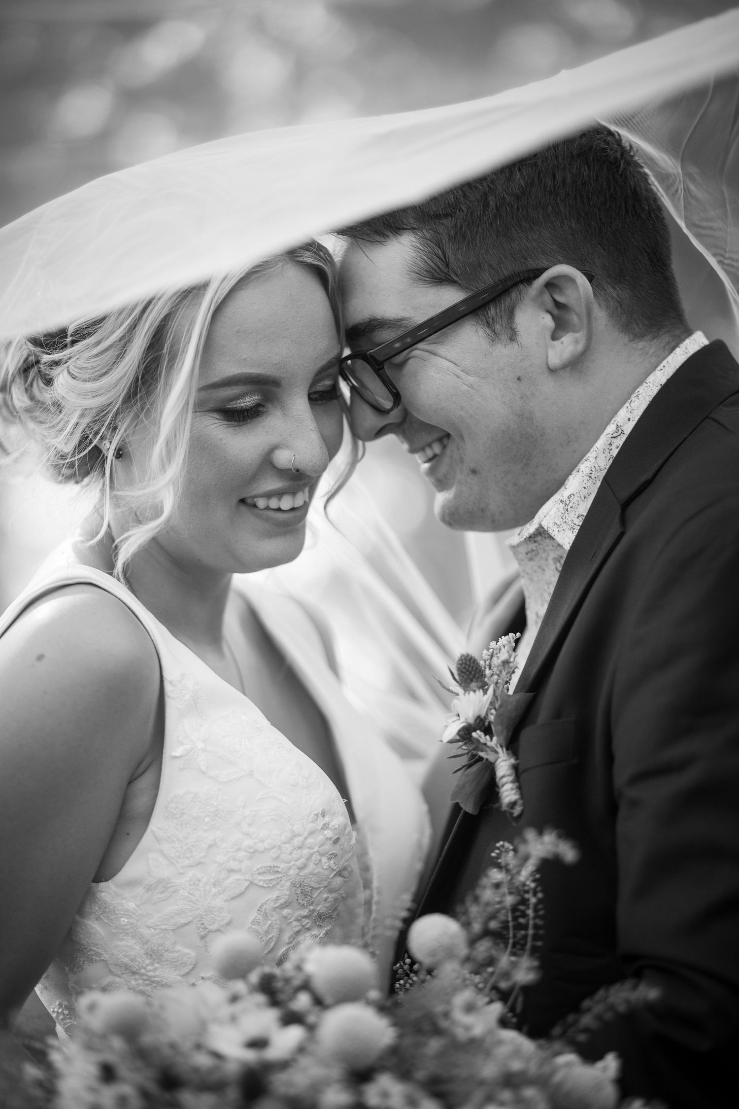 Intimate black and white wedding portrait under flowing veil.