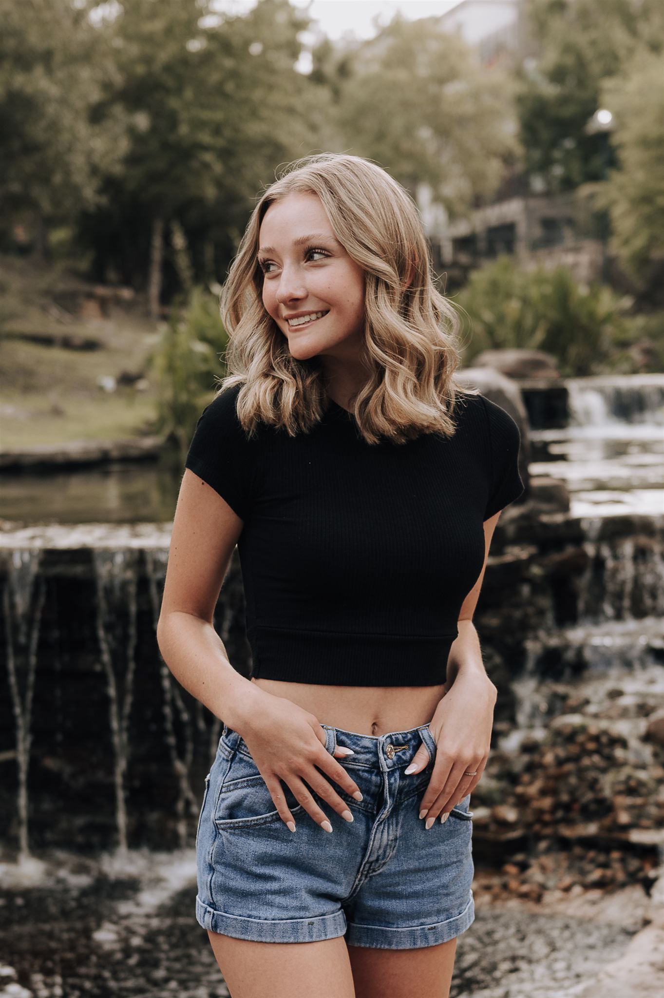 Lifestyle portrait by a scenic waterfall wearing summer casual attire.