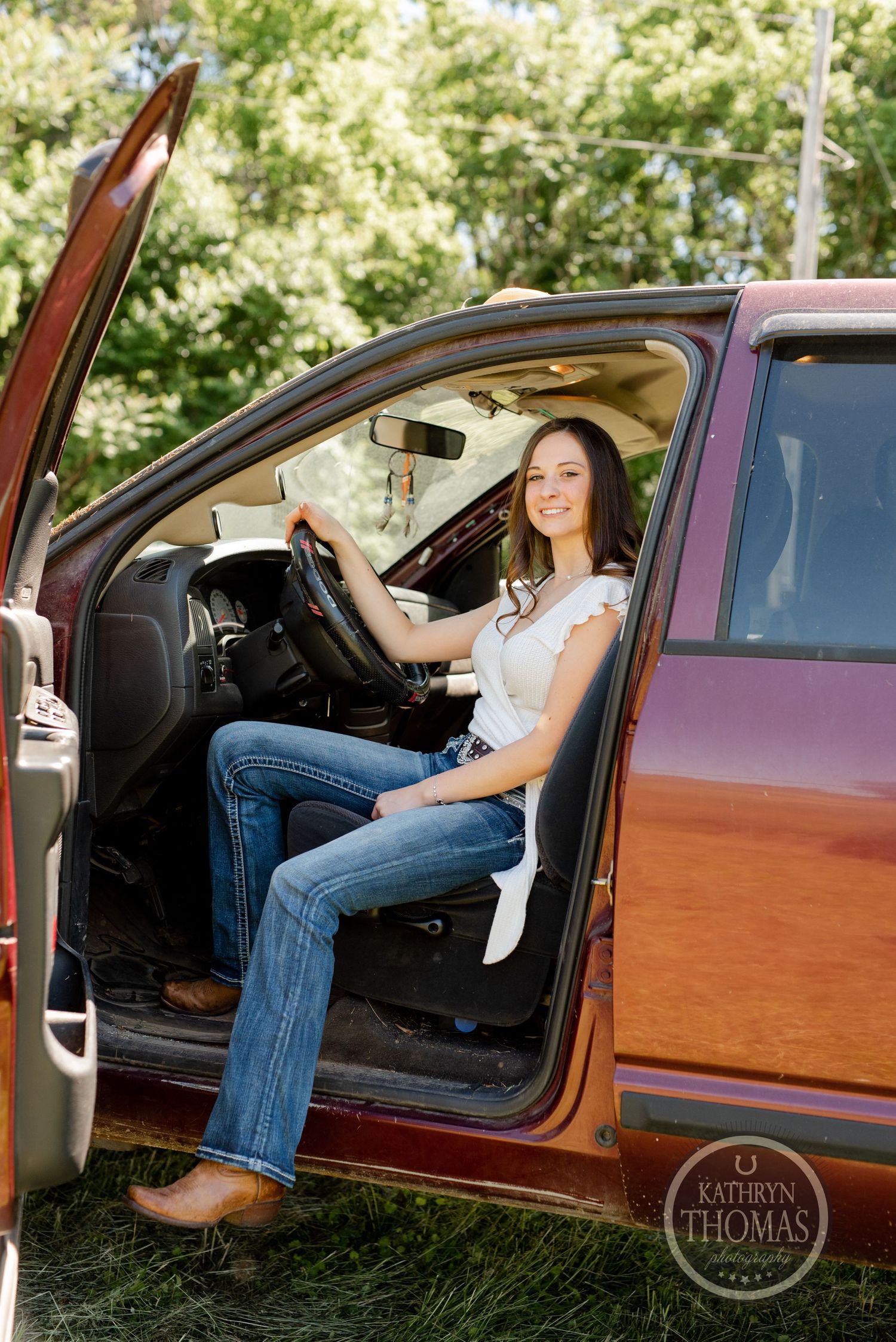 Person sits in driver's seat of red Ram 3500 truck with door open on sunny day.