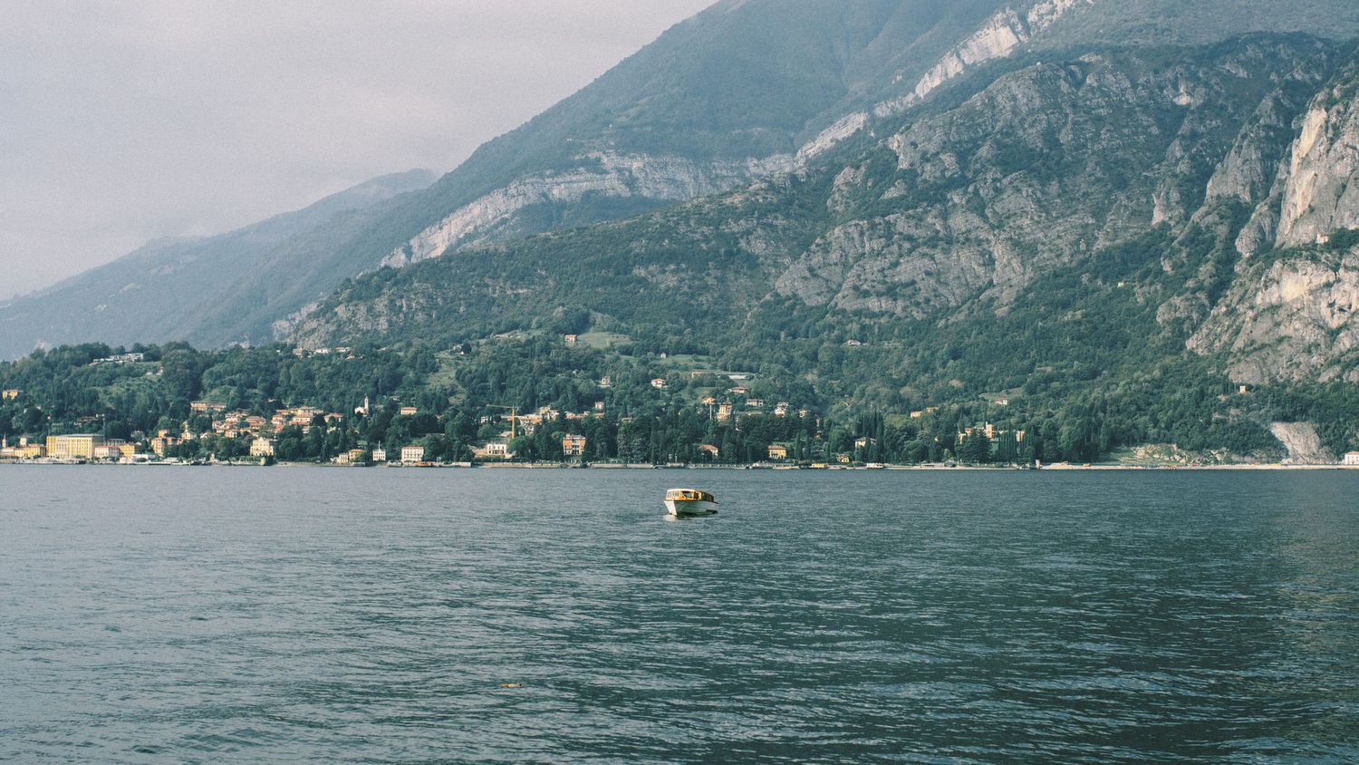 Scenic mountain lake view with boats and alpine landscape in the background.