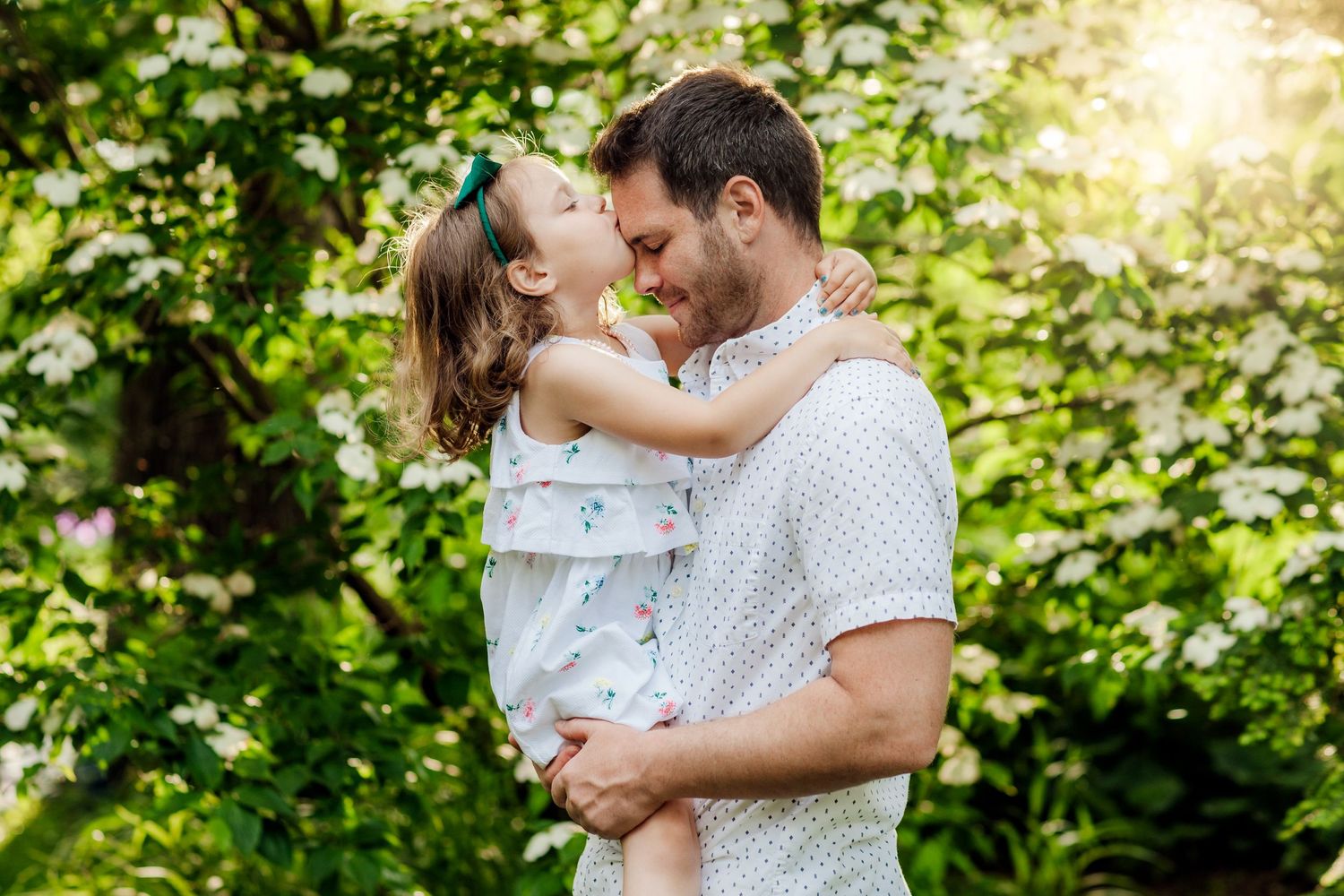 A tender embrace between parent and child sharing a joyful moment in a sunlit garden setting.