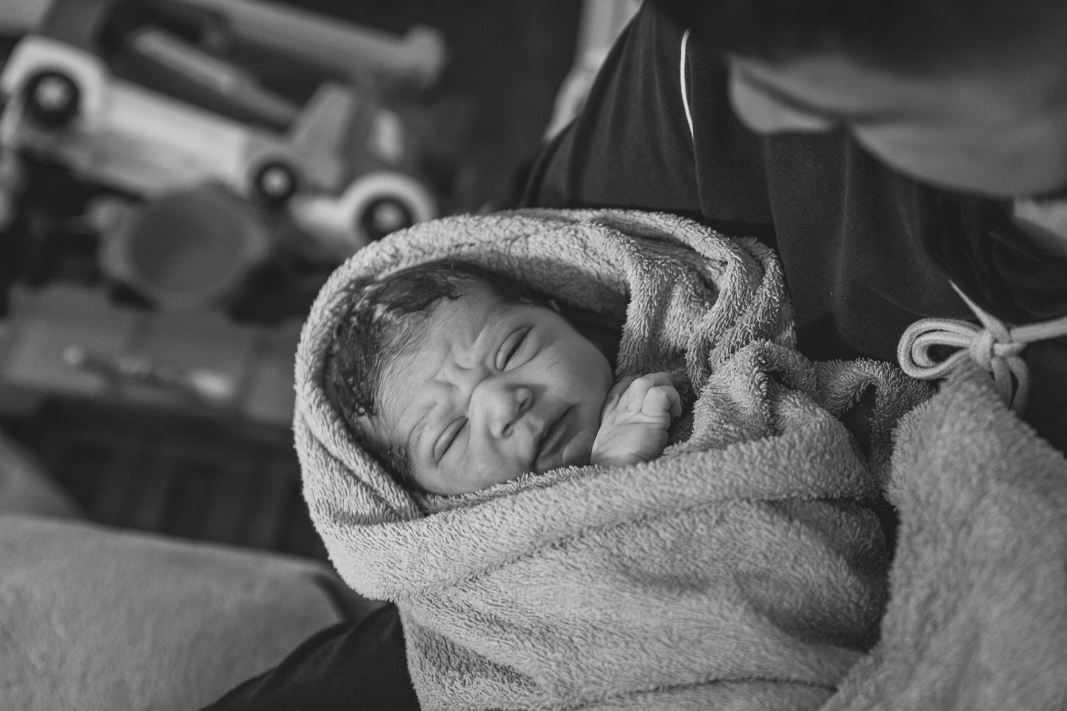 A sleeping newborn wrapped snugly in a soft gray blanket captured in black and white.