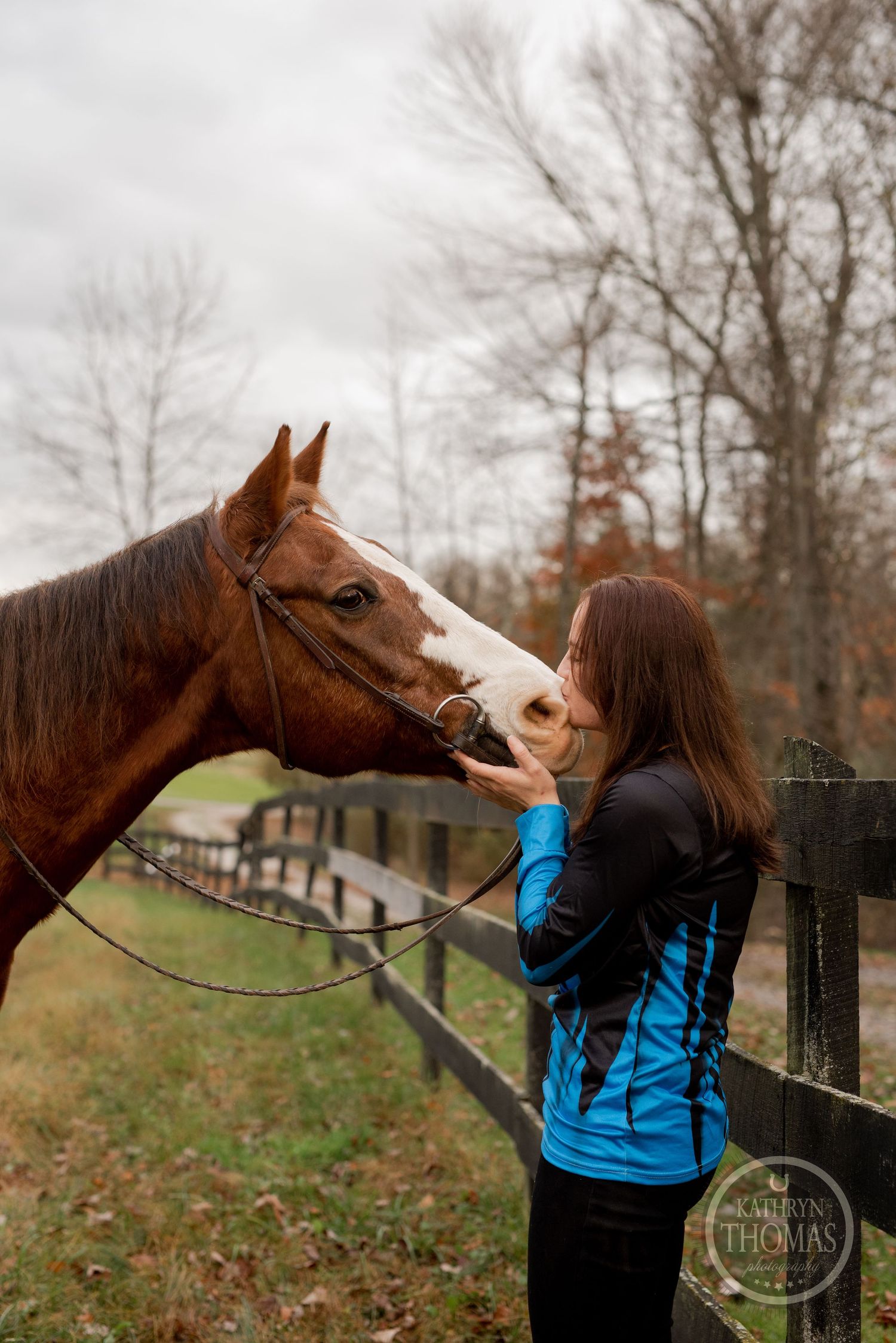 A sweet moment between handler and horse as they share an affectionate moment by the fence.