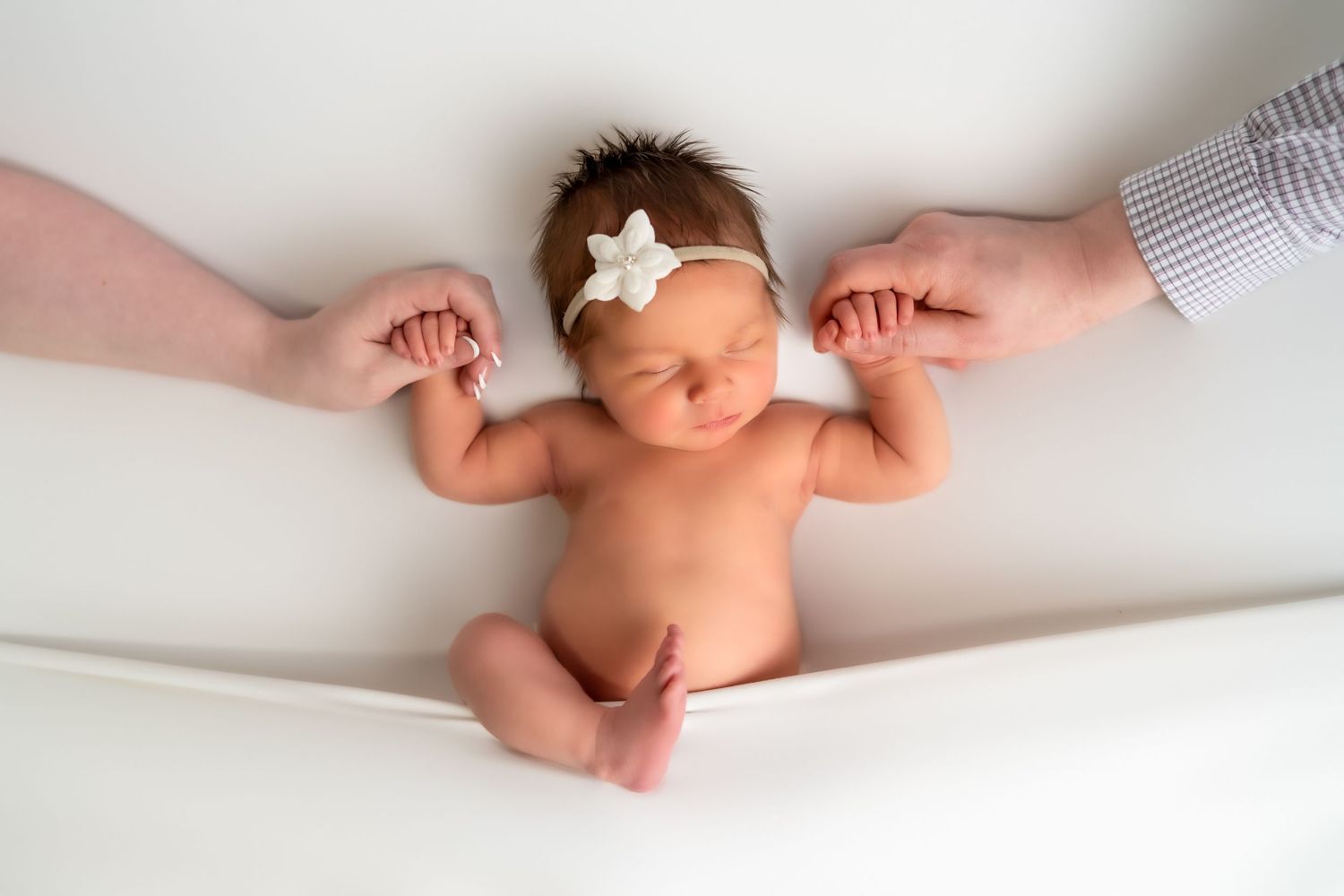 Close-up details of tiny newborn baby feet and hands against white background.