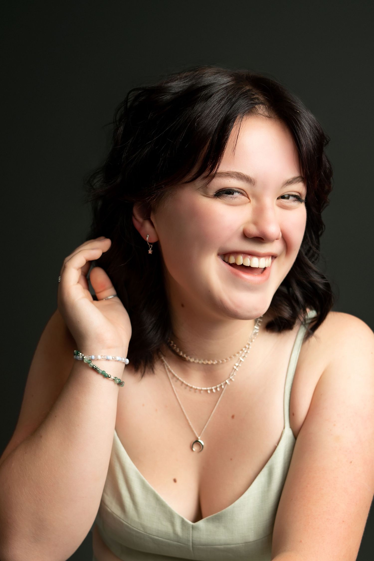 Portrait series showing joyful expressions and delicate jewelry against dark background.