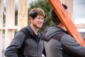 Construction workers having friendly conversation at building site wearing safety gear.