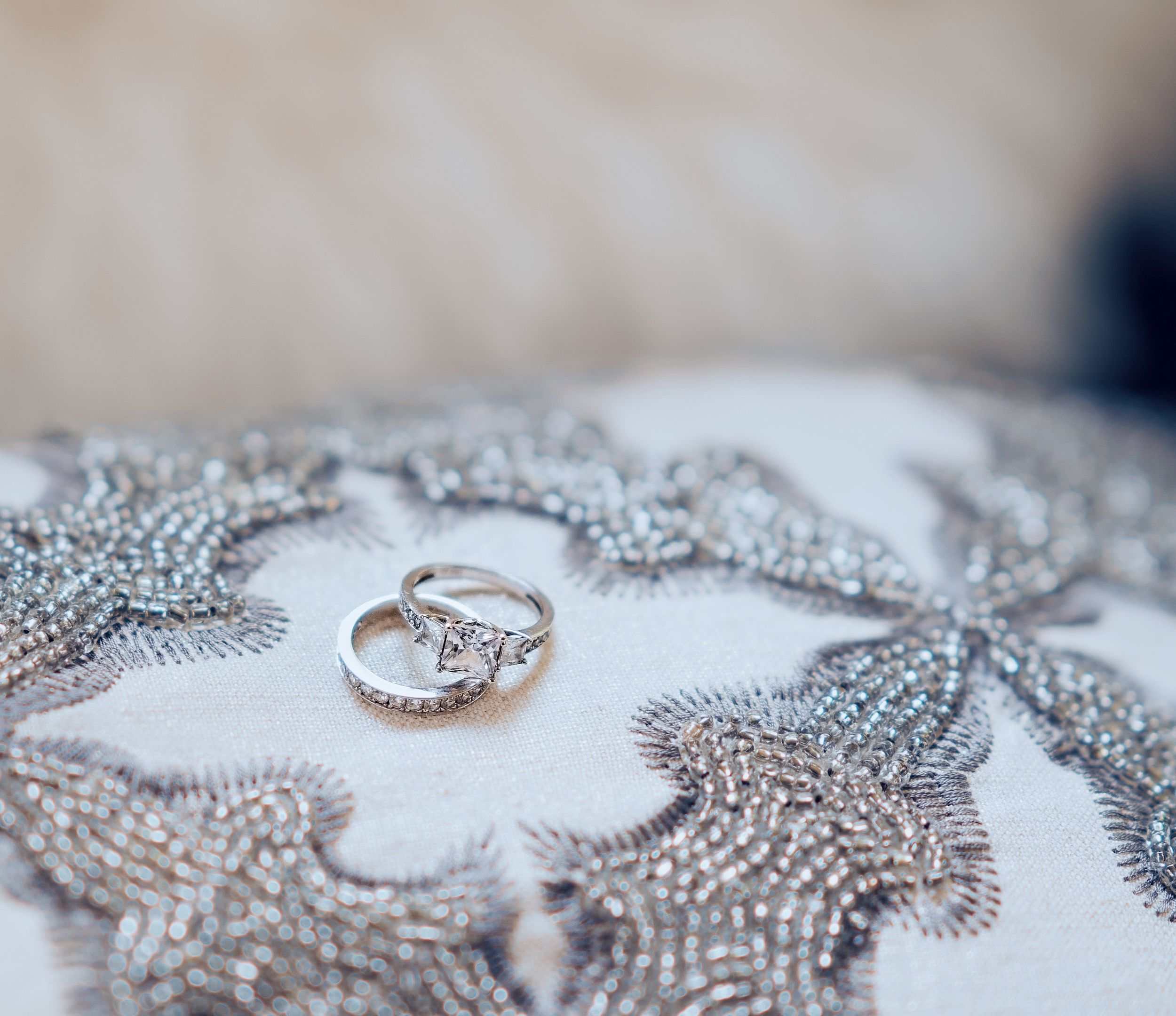 Wedding rings and jewelry sparkle on a textured silver surface.