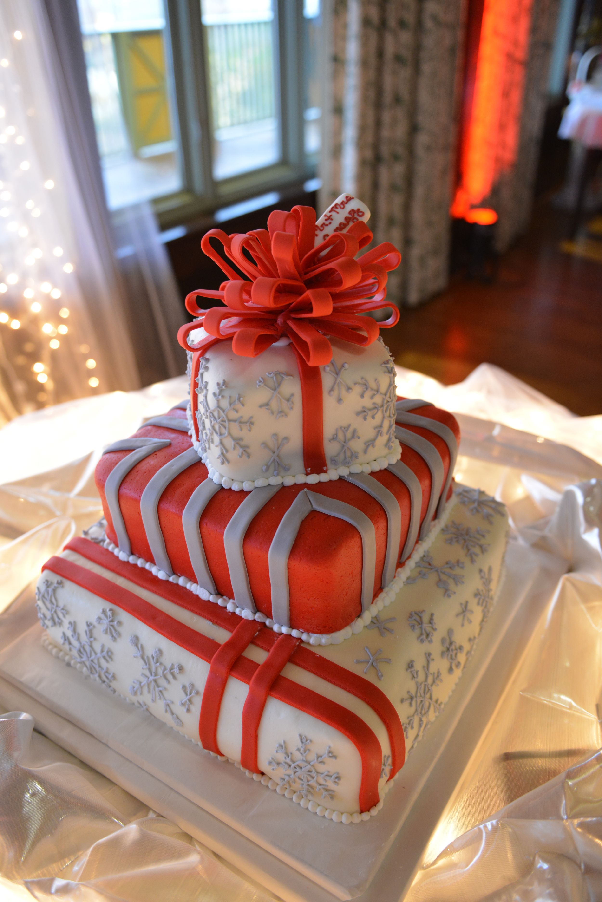 An elegant white and red striped wedding cake decorated with a large bow on top.