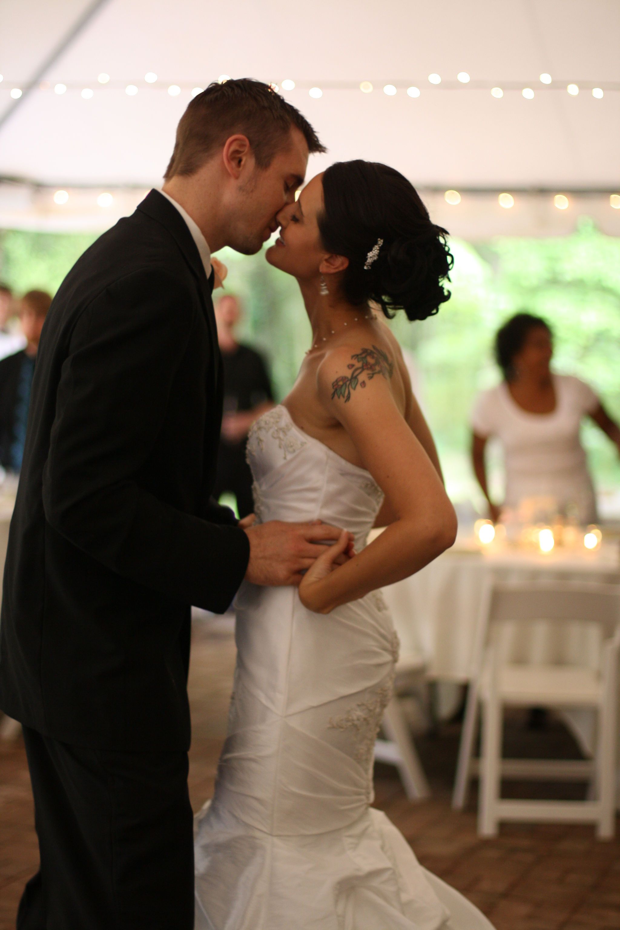 Couple sharing romantic dance moments under string lights at wedding reception.