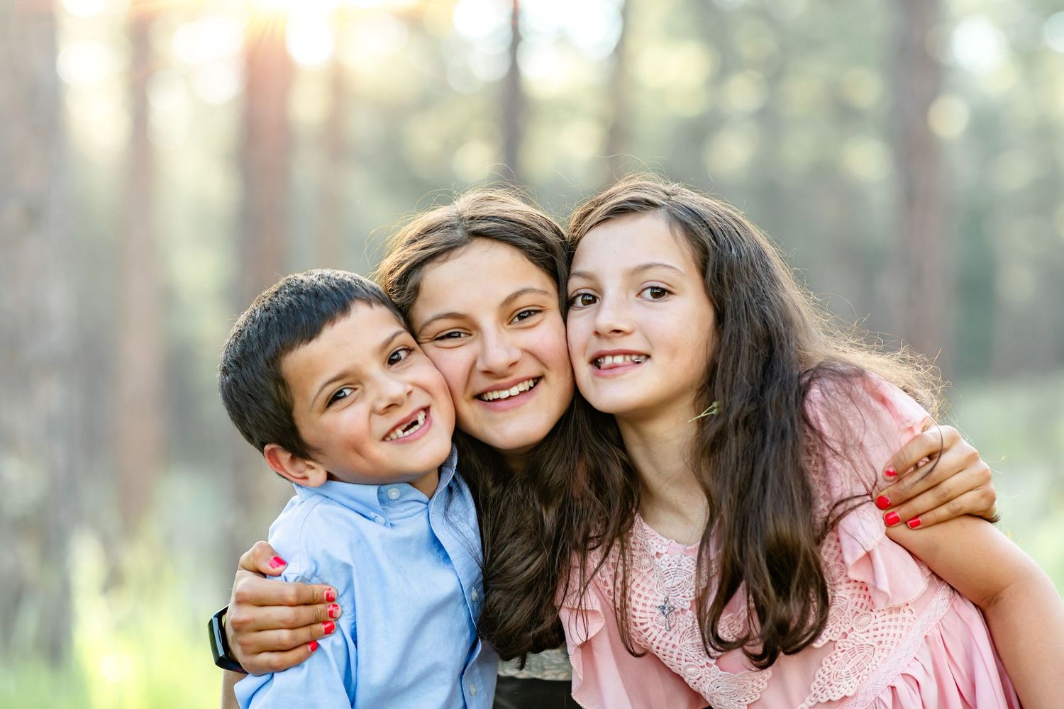 Three siblings smile and laugh with faces close together during their family session in Colorado Springs.