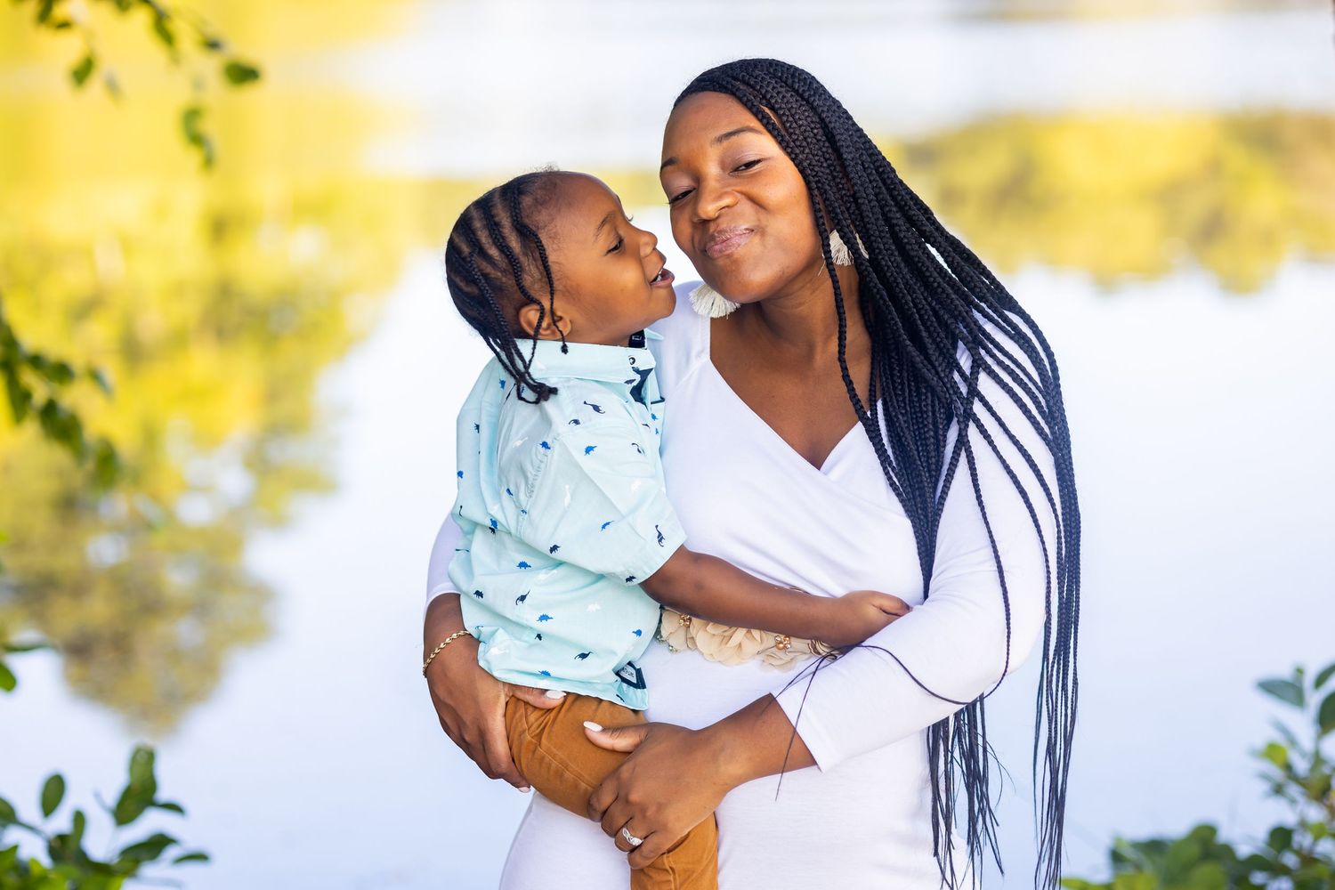 Tender moment between parent and child against scenic outdoor background.