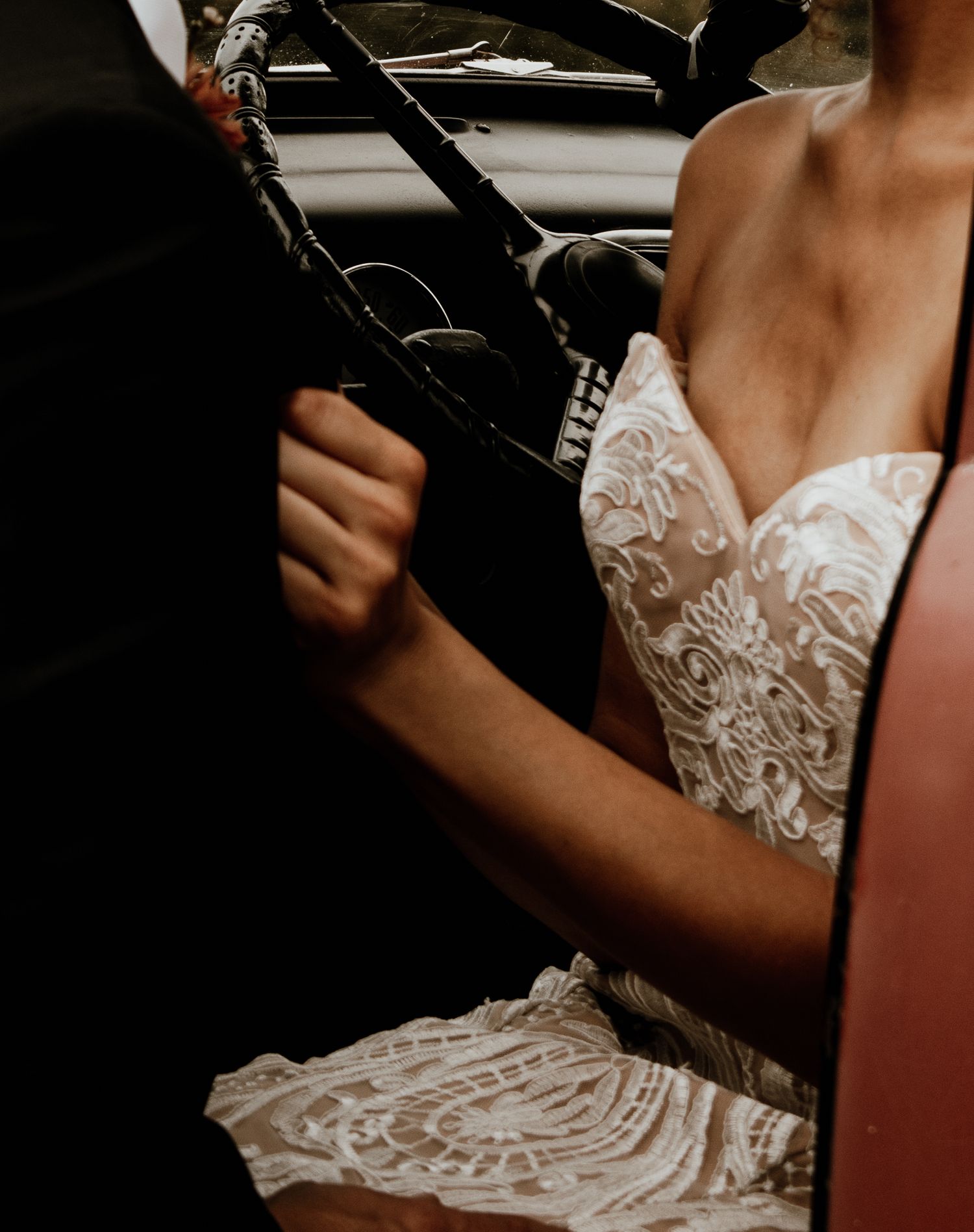 Detail shot of intricate lace wedding dress bodice against dark background.