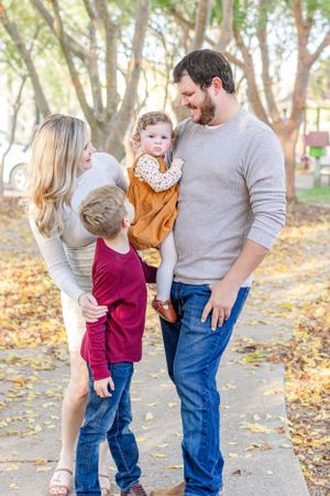Family shares candid moments together on wooded path during fall photo shoot.