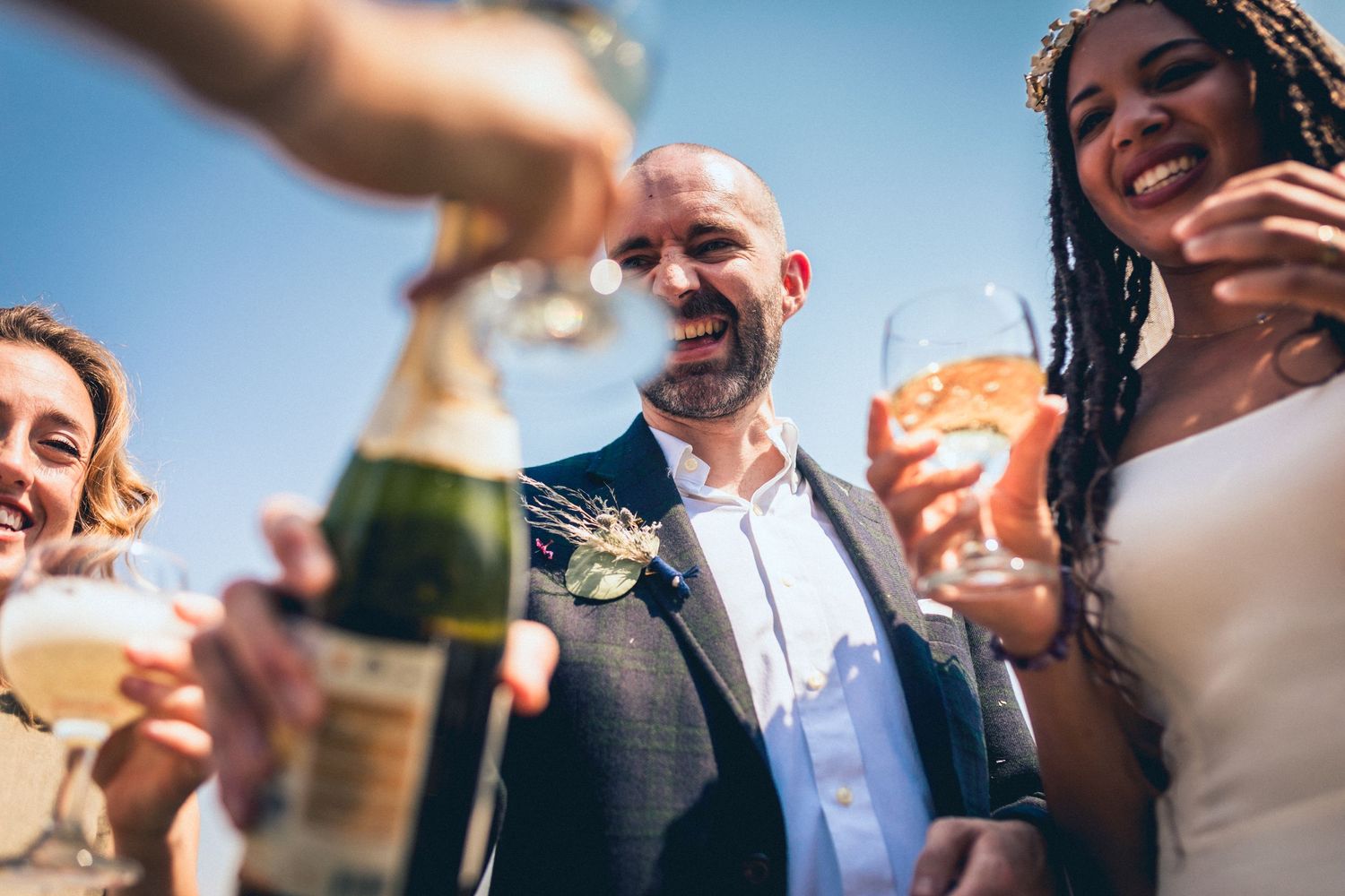 Wedding guests enjoying drinks and laughter during an outdoor celebration.
