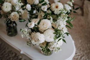 Elegant white garden roses and greenery arranged in clear glass vases.
