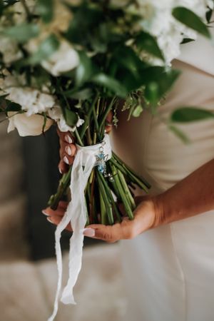 Close-up of white and green wedding bouquet wrapped with delicate ribbon.