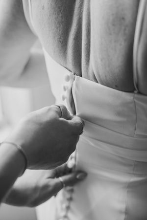 Black and white detail shot of dress being buttoned up.
