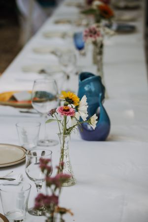 An elegant table setting with sunflowers in vases, wine glasses, and blue ceramic pitcher.