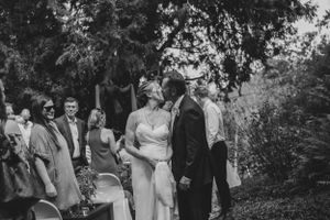 A black and white photo of a wedding ceremony in a garden setting surrounded by trees.