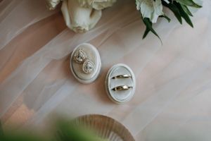 Wedding rings nestled in two oval-shaped vintage ring boxes on soft fabric.