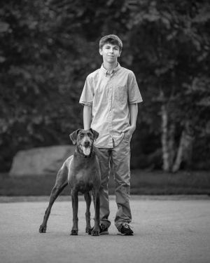 Black and white portrait of a standing person with their Great Dane dog.