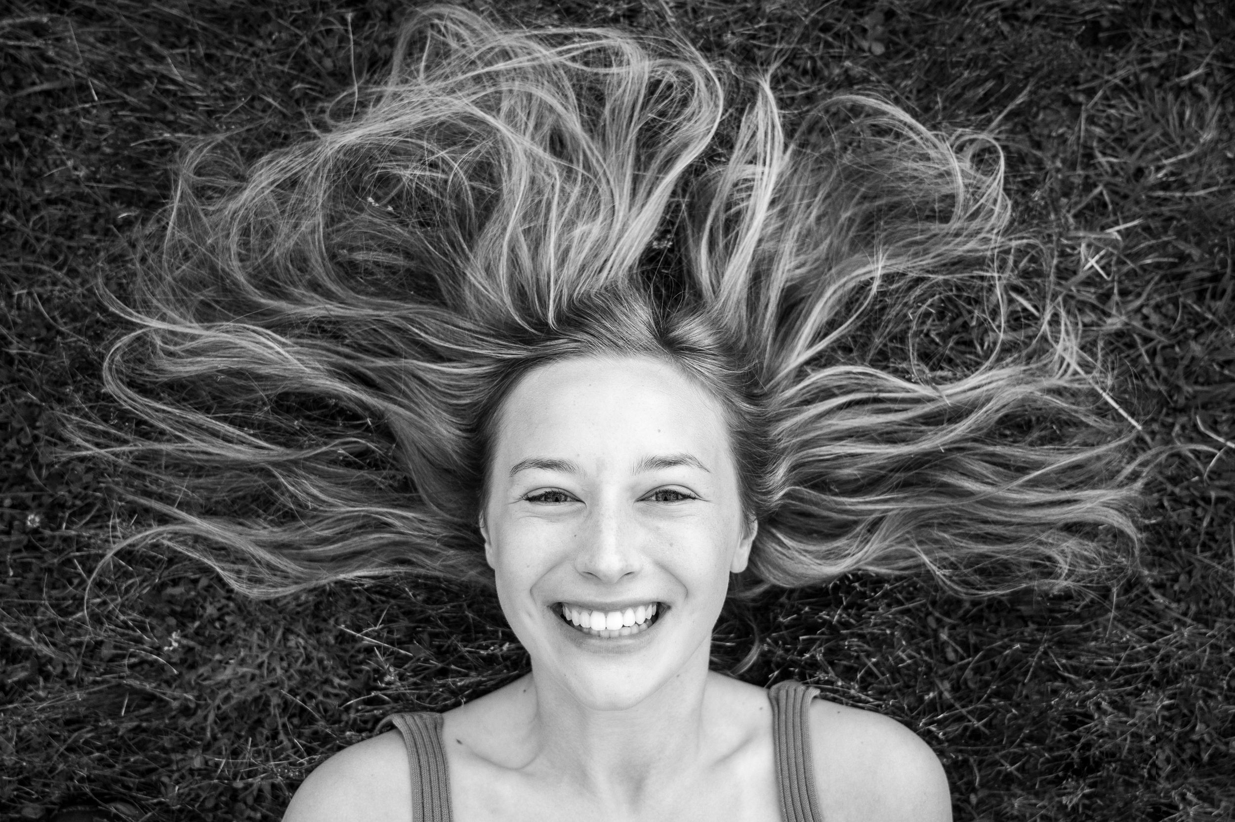Black and white portrait of someone with flowing hair spread out on ground.