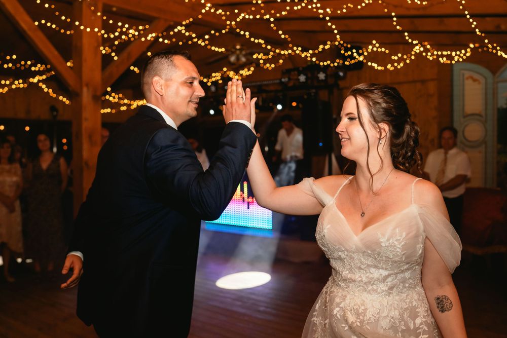 Wedding couple shares playful dance moves under string lights at their reception.