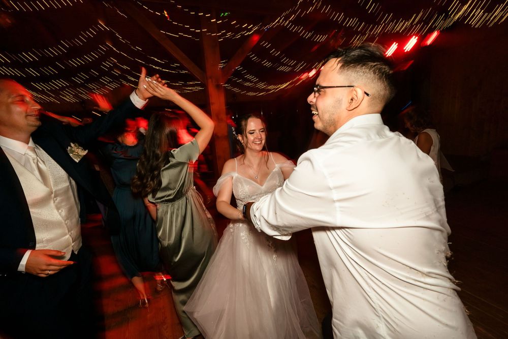 Wedding reception dance party with energetic dancing under string lights.