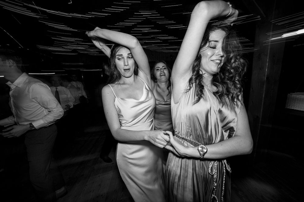 People dancing enthusiastically at a nighttime party with arms raised in celebration.