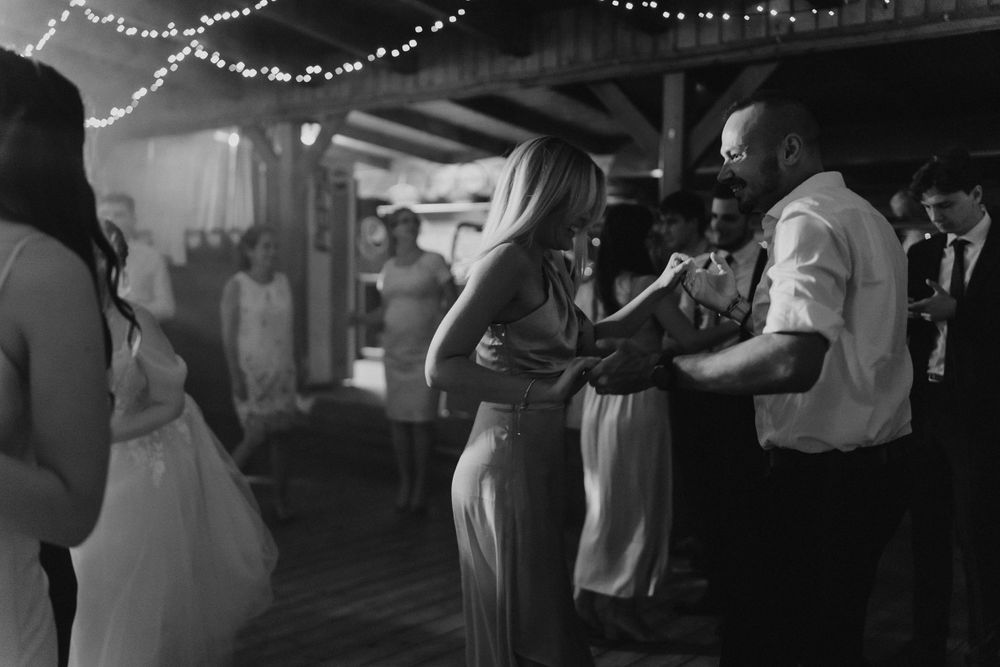 Couples slow dancing at an event decorated with string lights overhead.