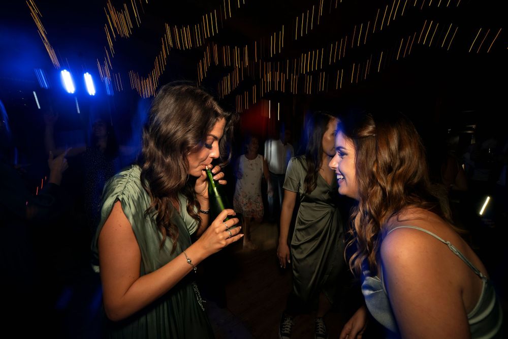 Friends chatting and laughing together at a dimly lit party with blue lighting.