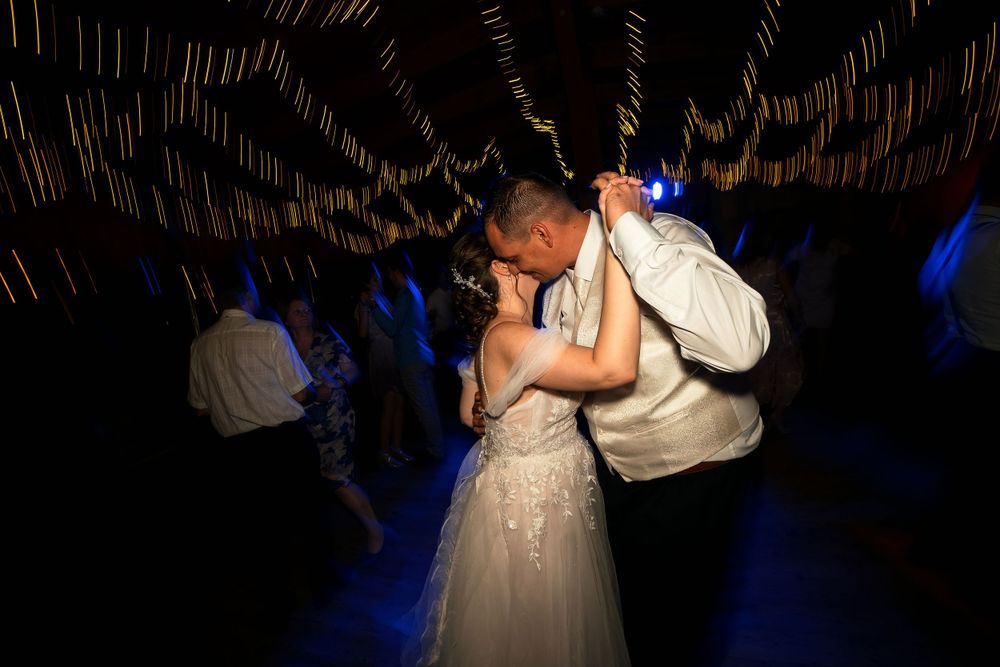 A couple sharing an intimate dance moment under blue spotlights at their wedding reception.