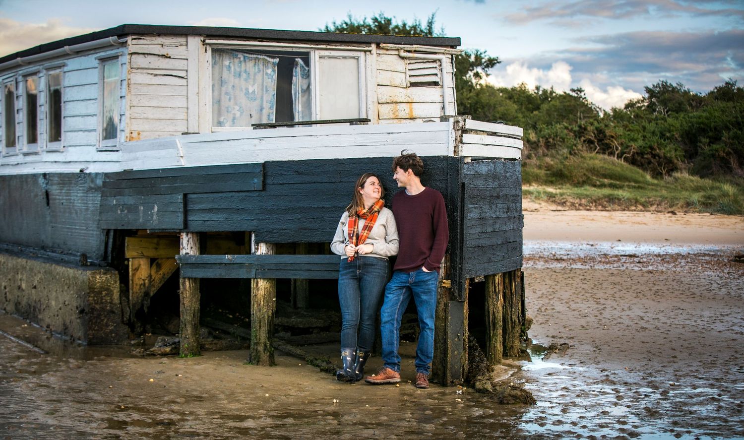 A romantic photoshoot by a waterfront building with moody cloudy skies.