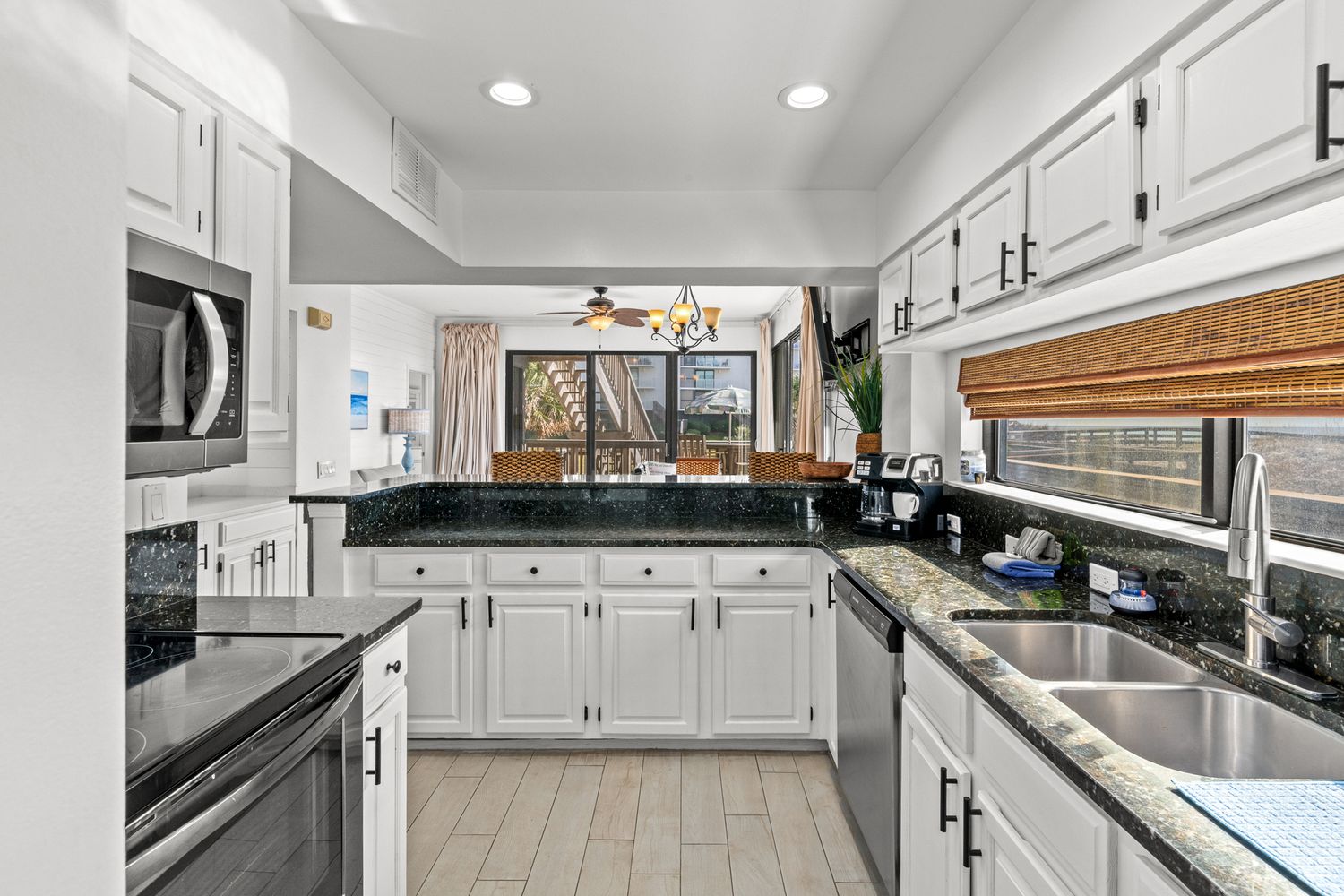 Modern white kitchen with dark countertops, stainless appliances and ample cabinet storage.