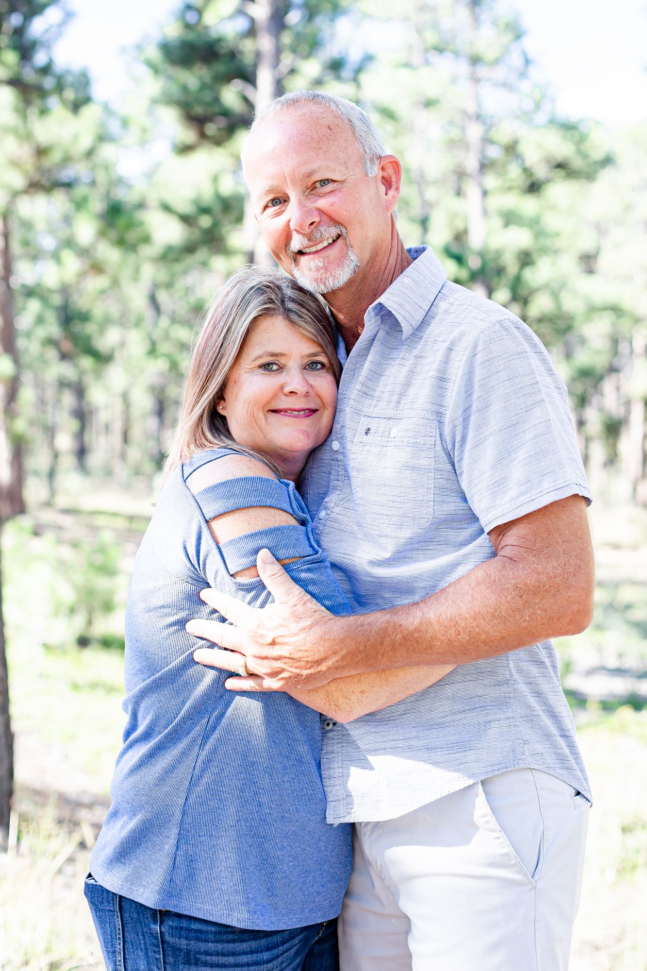 Husband and wife snuggle close and smile in Black Forest, Colorado.