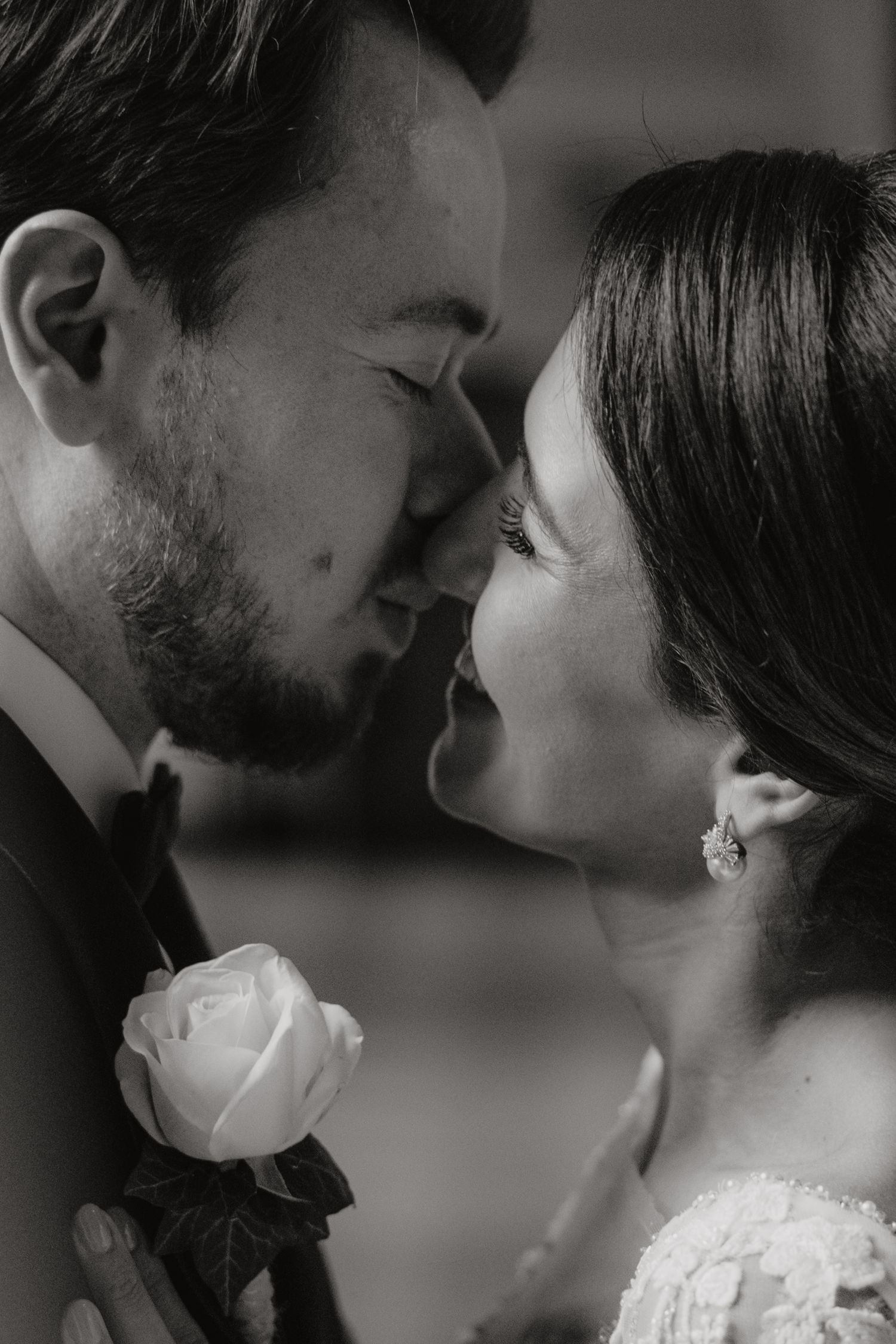 An intimate black and white close-up wedding portrait with a white rose boutonniere.