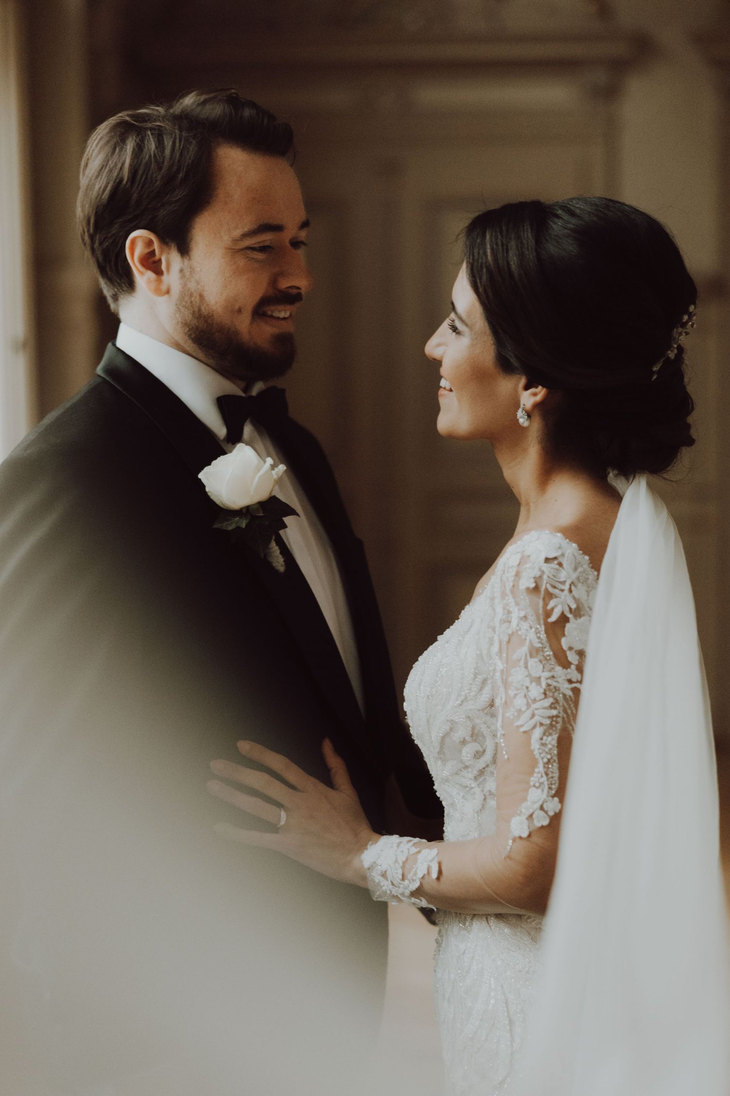 A warm, candid wedding moment captured in soft lighting under architectural arches.