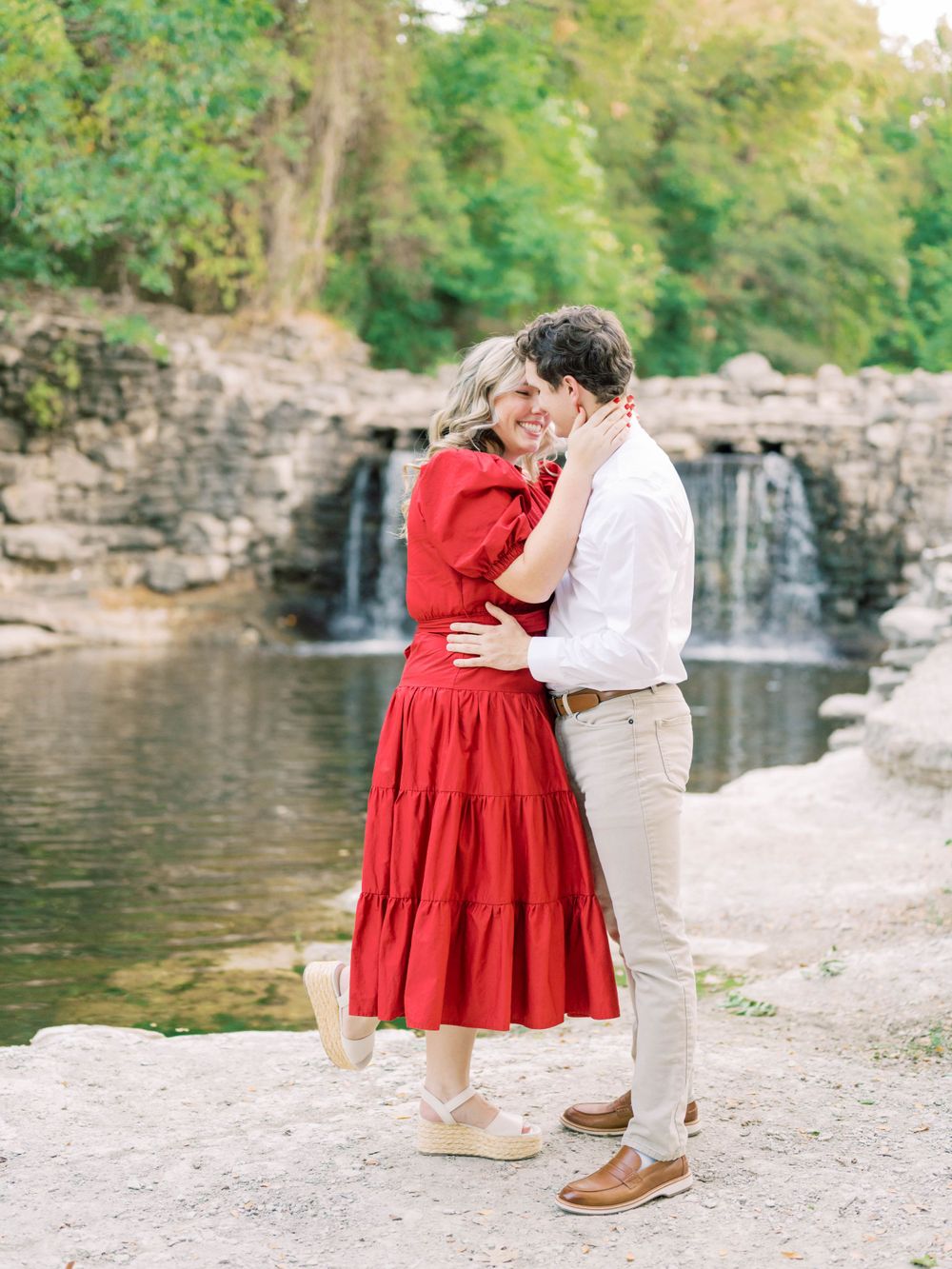 outdoor engagement session of a couple kissing in front of a waterfall