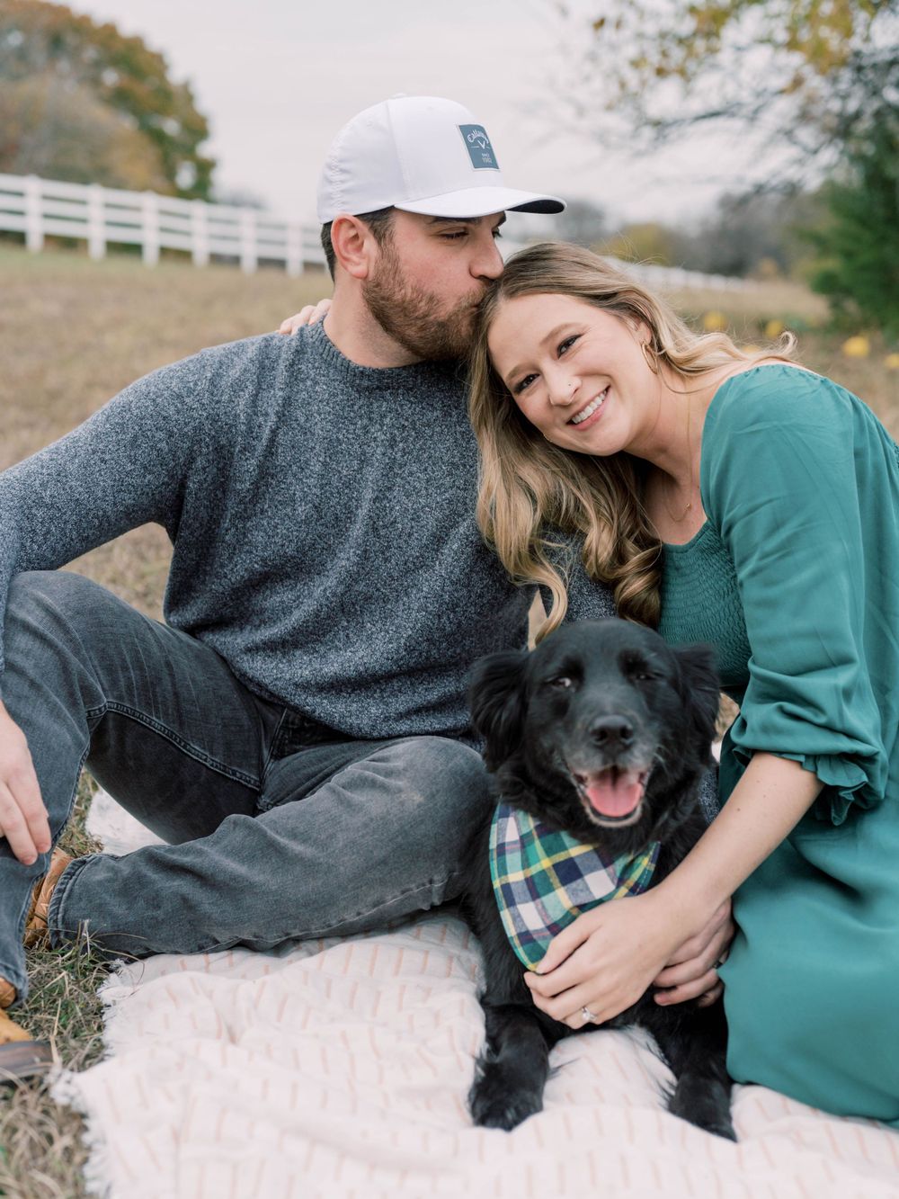outdoor family session of a man kissing his wife's head with their dog