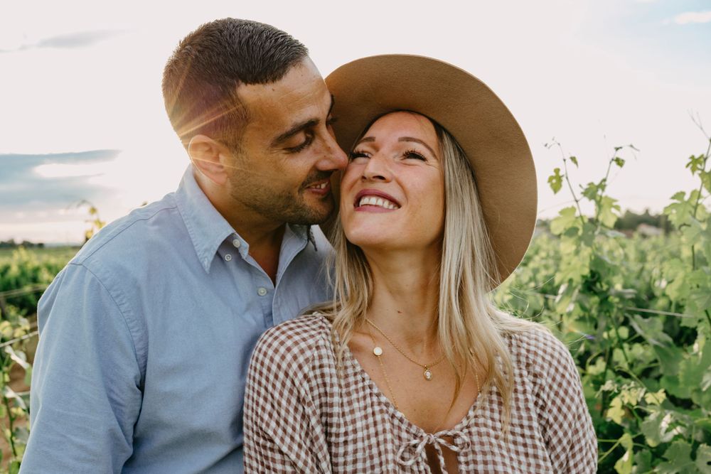 Couple sharing intimate moment among vineyard rows during golden hour.