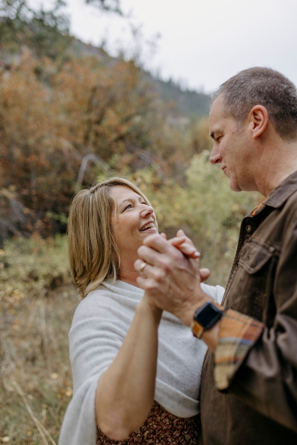 Couple sharing intimate moment outdoors with playful expressions and natural lighting.